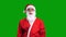 Santa Claus in red suit pointing up and to the corner on green chroma key background