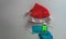 Santa claus red and white hat together with sanitary mask and person taking body temperature in lcd gun with copy space concept