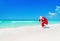 Santa Claus run along ocean beach with Christmas gifts sack