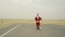 Santa claus with sack of presents is coming to town from the desert. Santa walks on sand in desert, found asphalt road