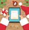 Santa claus is sitting at his workplace desk and receiving letter on his tablet