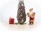 Santa claus on skis stands next to a christmas tree and a red gift in a tartan plaid on white winter