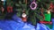 Santa Claus toy or doll is hanging on the Christmas tree next to the gifts