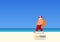 Santa Claus wearing mask walking on beach in new summer vacation concept. New normal travel after Corona Virus pandemic.