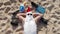 Santa Claus, wearing sunglasses, lies on sandy beach by the sea and sunbathes. top view. Santa summer vacation.