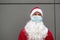 Santa Claus with white beard in red coat in a medical mask. Christmas in the coronavirus pandemic, seasonal diseases, SARS and