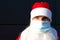 Santa Claus with white beard in red coat in a medical mask. Christmas in the coronavirus pandemic, seasonal diseases, SARS and pne