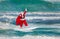 Santa Claus windsurfer with gifts sack surfing at ocean waves