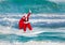 Santa Claus windsurfer with gifts sack surfing at ocean waves