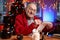 Santa claus writing christmas cards sitting at table in colourful room