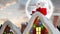 Santa clause on rooftop of a decorated house combined with falling snow