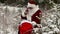 Santa Clause with smartphone near gift bag in the snowy woods