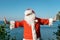 Santa doing exercises on the ocean. Traditional red outfit and relaxing on the beach