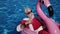 Santa floating in inflatable ring in swimming pool