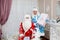 Santa and granddaughter Snow Maiden with gifts in the new year in a festive interior. New Year`s and Christmas