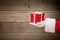 Santa hand holding a red gift box against wooden background