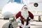 Santa With Hands On Hip Against Private Jet
