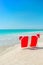 Santa hat on chaise longues at white sand beach against the sea