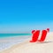 Santa hat on chaise longues at white sand beach against the sea