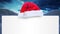 Santa hat over a blank placard against snow falling on winter landscape