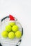 Santa hat on tennis ball, set of tennis balls in shape fir tree on racket on white snow winter background. Merry Christmas and New