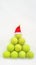 Santa hat on tennis ball on white snow background. Christmas and New year concept with tennis balls. Yellow green color tennis