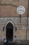 Santa Maria della Scala entrance and ancient clock 1643 AD with only hours hand. Siena, Tuscany, Italy.