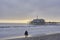 Santa Monica pier in the evening, a couple standing at the beach, seabirds flying in the sky, sea buoys in the pacific, the last