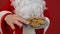 Santa on a red background takes chocolate Christmas cookies from a plate. Close up