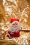 Santa`s toy with a red costume and hat and a white beard and gilded glasses, isolated on a shiny orange background with bokeh.
