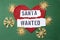 Santa wanted written on white paper strips,  Santa for hire sign