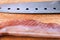 Santoku Knife with Holes and Fat Salmon Abdomen or Belly on a Wooden Cutting Board