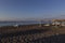 Santorini black beach Perissa, Perivolos illuminated by the morning rays of the sun. In the right parasols with sunbeds, a white-