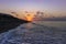 Santorini, black pebble beach of Perivolos, Perisa at sunrise. Sea waves, beach chairs and umbrellas, beautiful sky with clouds