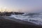 Santorini, coast at Vlychada at sunrise, beautiful clear sky, stormy sea crashing into rocks at the coast. Behind the stones is a