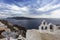 Santorini - Oia, view from the cliff to the caldera. White bell tower on the right and a white roof on the left on the cliff of
