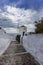 Santorini - Oia, Windmill, a stone path with a high white wall leading to a windmill. Beautiful sky with dramatic clouds