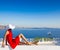 Santorini travel tourist brunette woman in red dress visiting famous white Oia village.