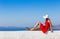 Santorini travel tourist brunette woman in red dress visiting famous white Oia village.