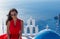 Santorini travel tourist brunette woman in red dress visiting Fira city.