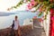 Santorini traveler man walks in Thera by flowers, Greece enjoying Caldera landscape. Tourism, traveling, summer vacation