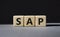 SAP - Systems Applications Products. Wooden cubes with word SAP. Beautiful grey background. Business and System Application