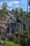 Sapokka Park in the city of Kotka in Finland. Waterfall with a cliff on the background of the lake, tourists on the bridge