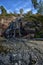 Sapokka Park in the city of Kotka in Finland. Waterfall with a cliff on the background of the lake, tourists on the bridge