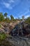 Sapokka Park in the city of Kotka in Finland. Waterfall with a cliff on the background of the lake, tourists on the bridge