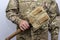 A sapper shovel in a closed case in the hand of an American military on a light background.