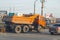 Saratov, Russia - 04/11/2020: Road works of community services, an orange KamAZ special truck and a warning sign on the asphalt in