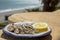 Sardines espeto prepared on skewers and open flame on fireplace with olive trees wood, served outdoor and view on blue sea, Malaga