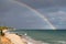 Sardinian coast, rough sea and cloudy sky after the rain with a rainbow that is born on the sea. Rainbow over the sea after a