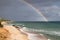 Sardinian coast, rough sea and cloudy sky after the rain with a rainbow that is born on the sea. Rainbow over the sea after a